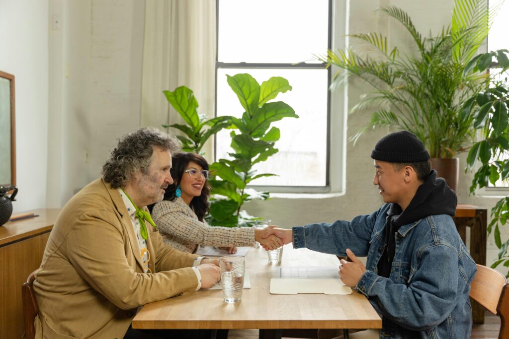 Diverse group of business people shaking hands in an office setting with indoor plants.